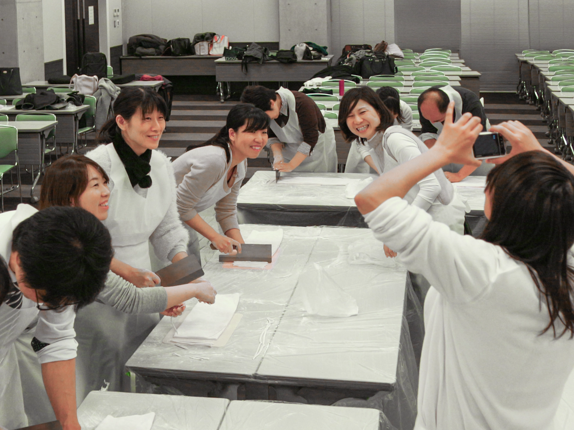 広い会場に複数チームが並んで作業している出張うどん作り体験の全景