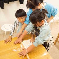 上から見た、子供たちが一生懸命生地を伸ばす場面（Top-down view of children working hard to roll out the dough） 手打ちうどん作り体験教室 2026年1月 A6408414-4.jpg – イリコスキー製麺所