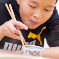 自分で作ったうどんを美味しそうに頬張る男の子 / A boy happily eating the udon he made himself. 手打ちうどん作り体験教室 2026年2月 A6408881-1.jpg – イリコスキー製麺所