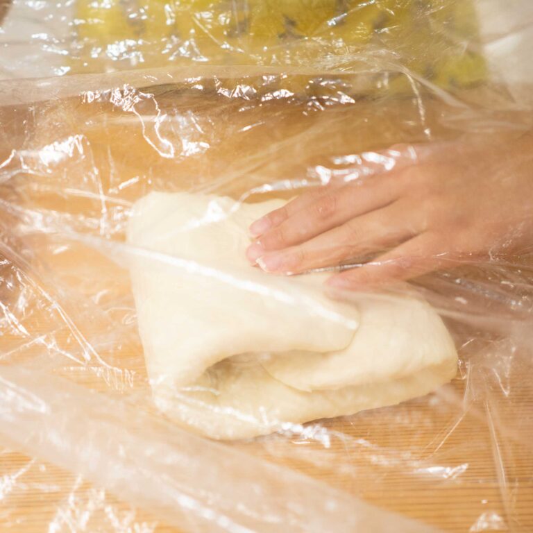 3回目の1年生、ひとりで完走！ 手打うどん作り体験教室 2026年1月 shaping-udon-dough-through-plastic-wrap.jpg – イリコスキー製麺所