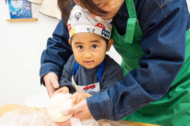 父に手を添えてもらいながら生地を丸める男の子。大きな目でカメラを見つめている。 手打ちうどん作り体験教室 2026年2月 udon-class-boy-shaping-dough-2.jpg – イリコスキー製麺所