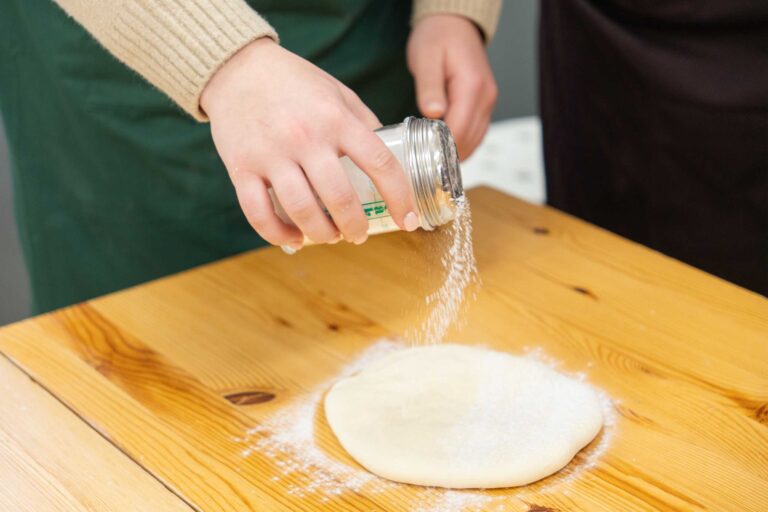 うどん体験教室で作業台の生地に打ち粉をふりかける手元 手打うどん作り体験教室 2026年1月 udon-class-dusting-flour.jpg – イリコスキー製麺所
